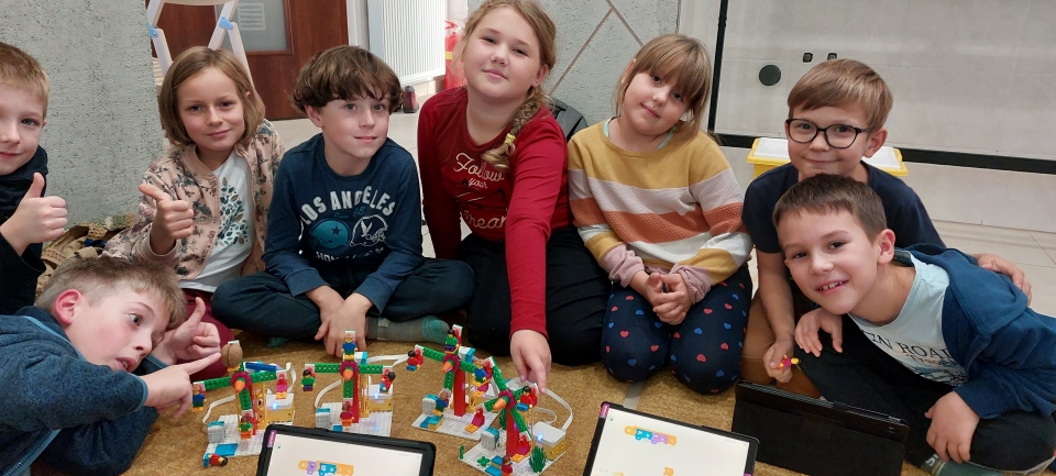 Cała grupa dzieci z robotami LEGO zbudowanymi podczas warsztatów robotyki FA-BRYKA w Poznaniu